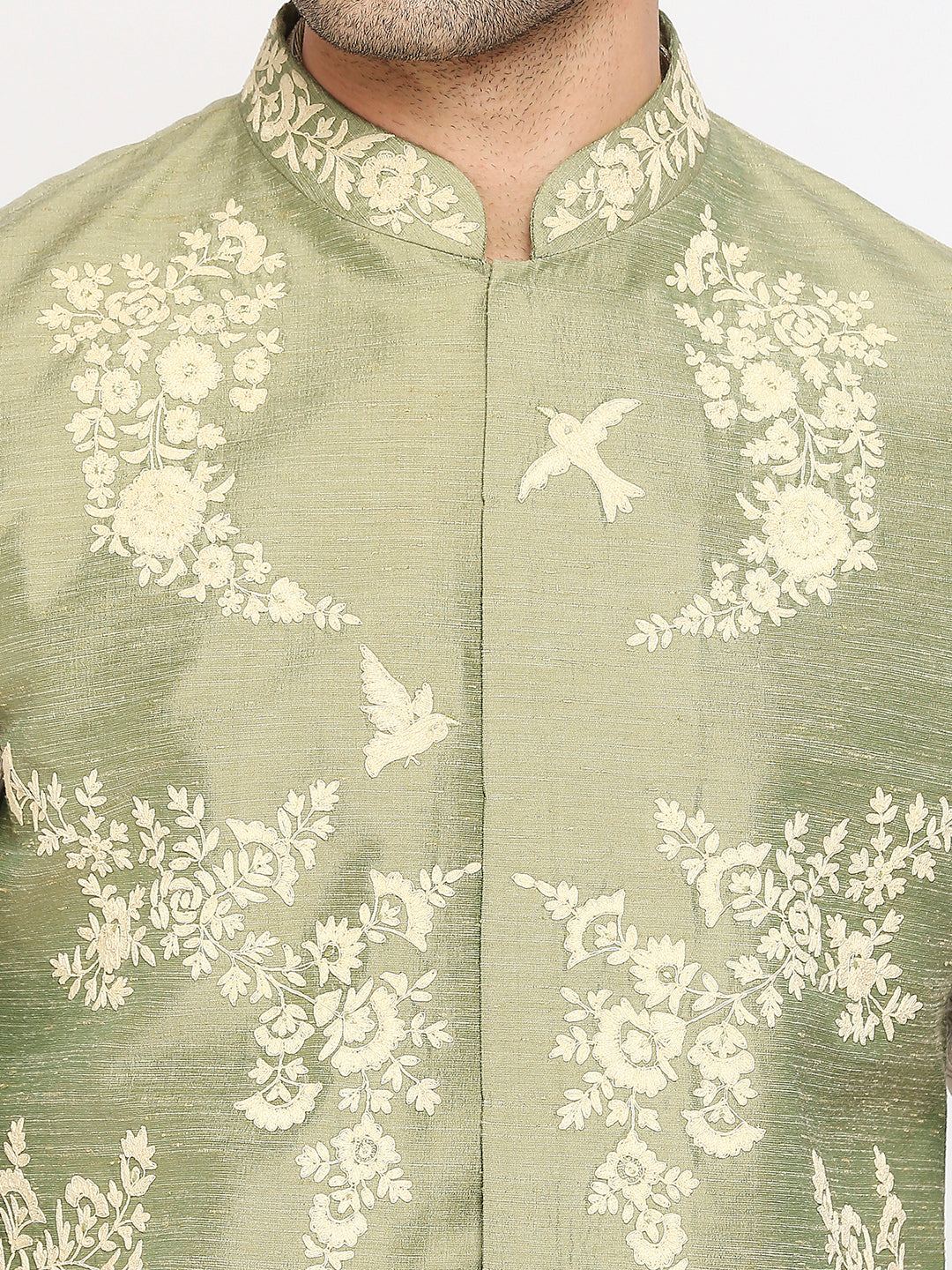 Close-up of a men's traditional jacket or kurta in sage green with cream floral and bird embroidery, featuring a mandarin collar and front button closure.