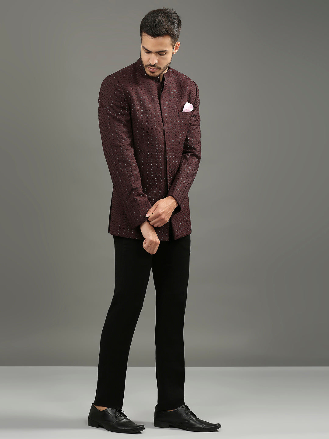 Featuring a wine-colored bandhgala adorned with intricate cutdhana handwork, this ensemble is paired with classic black formal pants. A refined yet festive statement, it's the perfect choice for a sangeet.
