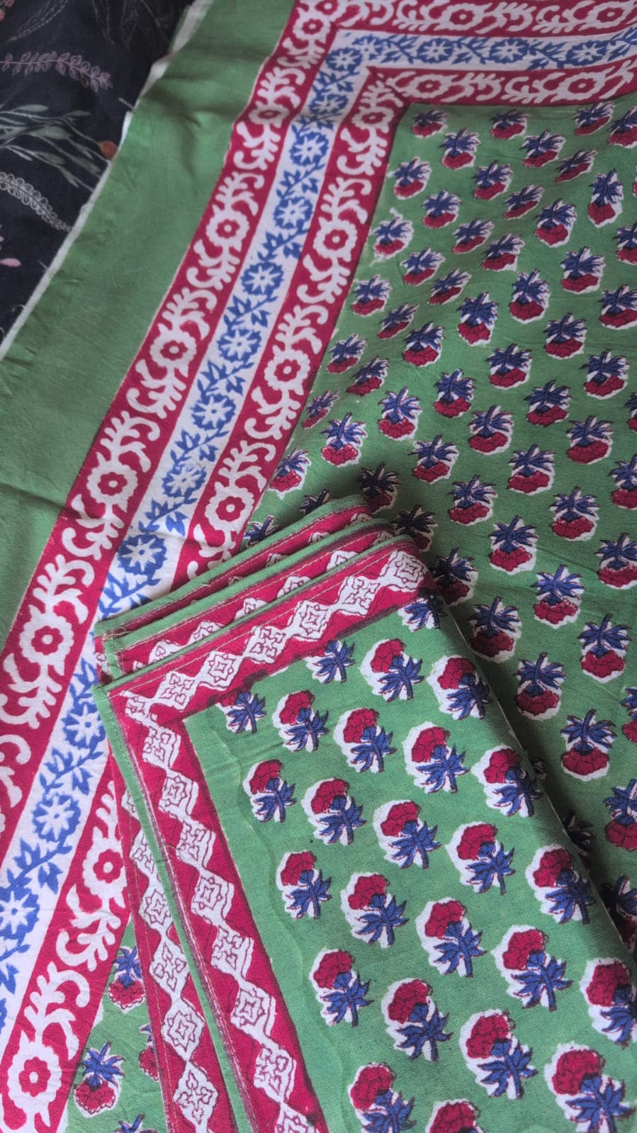 Textile with red, blue, and white patterns on a green background