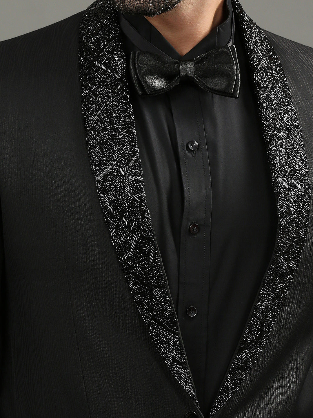 Black tuxedo with decorative lapels and a bow tie on a gray background